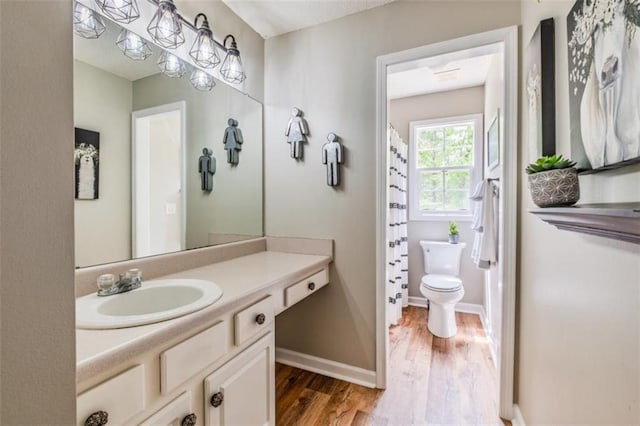 full bath featuring vanity, toilet, baseboards, and wood finished floors