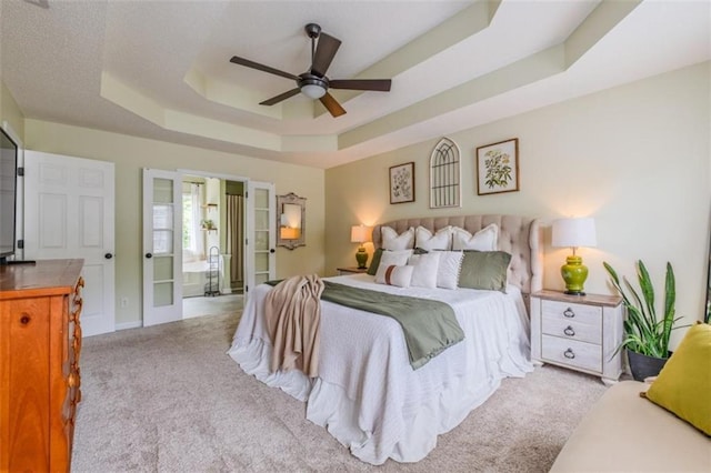 carpeted bedroom featuring a tray ceiling and ceiling fan