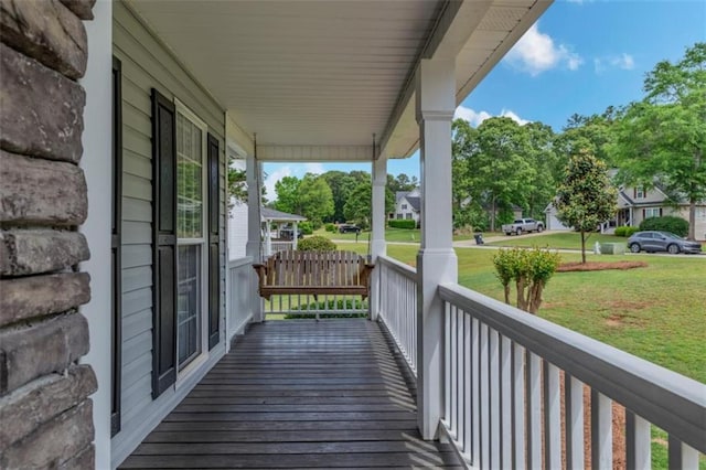 wooden terrace featuring covered porch and a yard