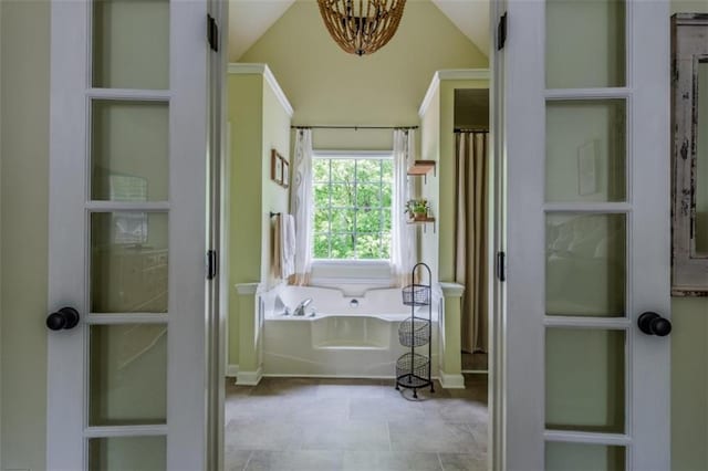 full bath featuring a chandelier, lofted ceiling, baseboards, and a bath