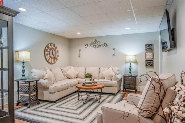 living area with a paneled ceiling, recessed lighting, and wood finished floors