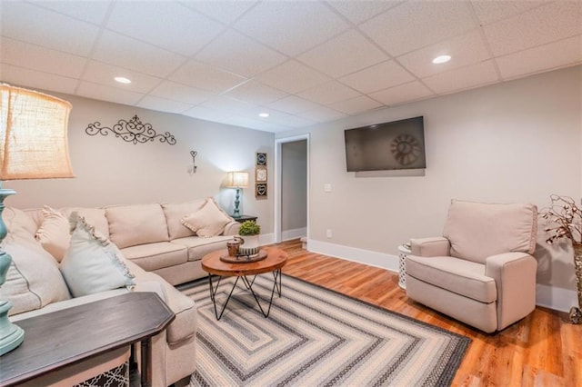 living room featuring baseboards, a drop ceiling, recessed lighting, and wood finished floors