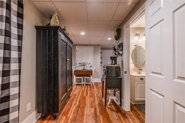 hallway featuring recessed lighting, wood finished floors, baseboards, and a drop ceiling