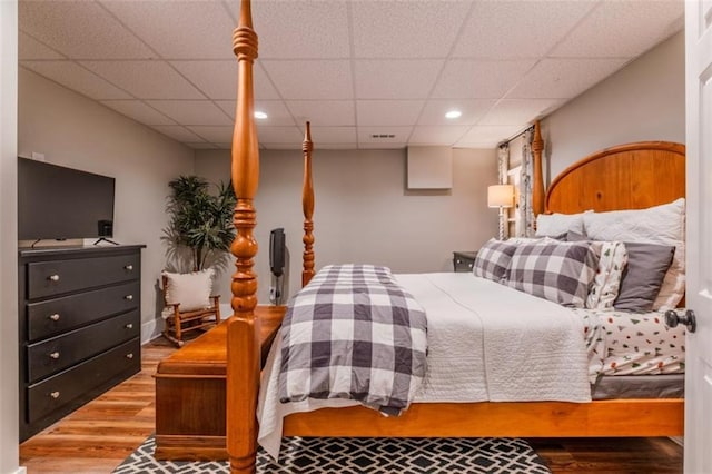 bedroom with a drop ceiling, recessed lighting, and wood finished floors