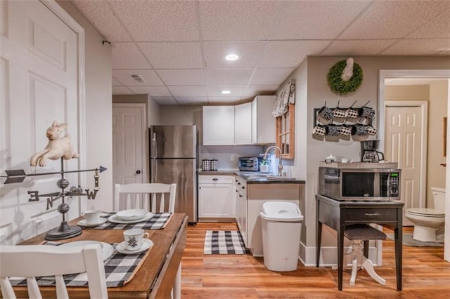 kitchen featuring recessed lighting, light wood finished floors, white cabinetry, a paneled ceiling, and stainless steel appliances