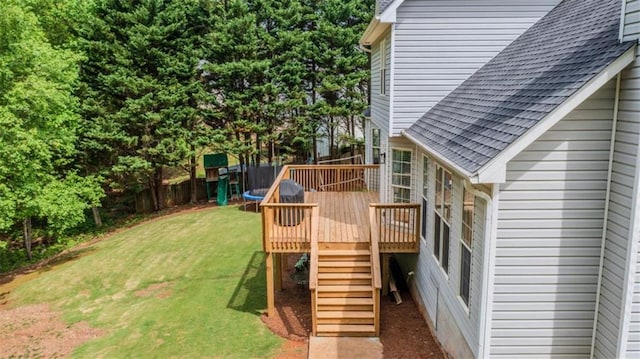 view of yard featuring a trampoline, a deck, stairs, and fence