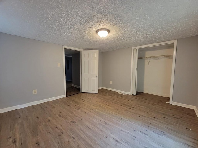 2940 Grand Ave SW, Atlanta, GA 30315 - unfurnished bedroom featuring a closet, a textured ceiling, baseboards, and wood finished floors
