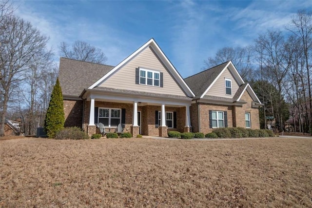 craftsman-style house featuring a front yard, a porch, and brick siding