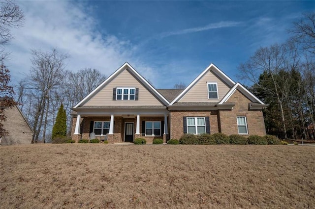 craftsman-style home featuring a porch, a front yard, and brick siding