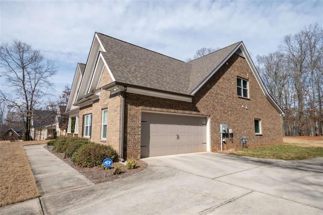 view of side of property featuring concrete driveway, brick siding, and roof with shingles