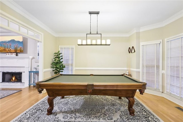 playroom with wood-type flooring, ornamental molding, billiards, and a tiled fireplace