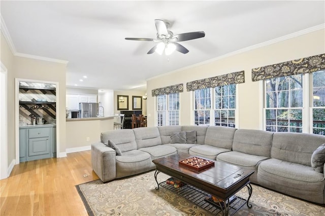 living room featuring ceiling fan, crown molding, and light wood-type flooring