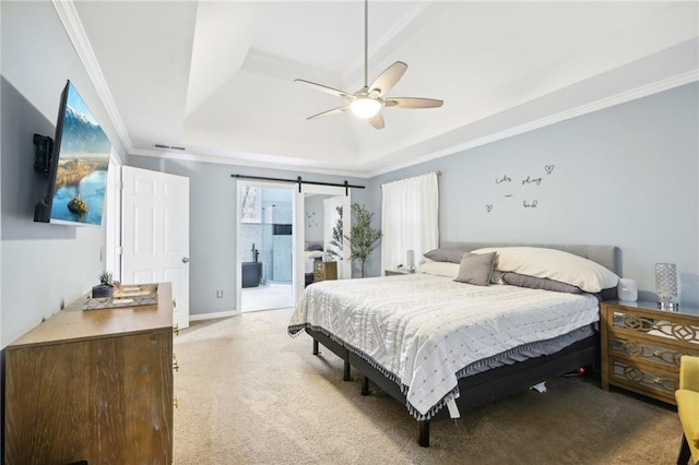 bedroom featuring ceiling fan, ensuite bathroom, light colored carpet, a tray ceiling, and ornamental molding