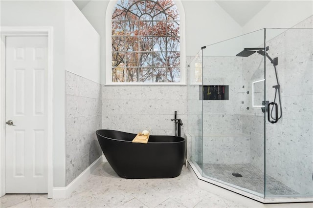 bathroom with separate shower and tub, tile walls, and lofted ceiling