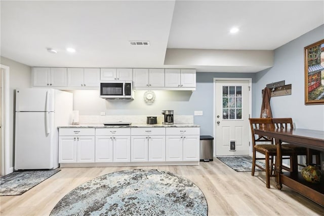 kitchen with light hardwood / wood-style floors, white fridge, cooktop, and white cabinetry