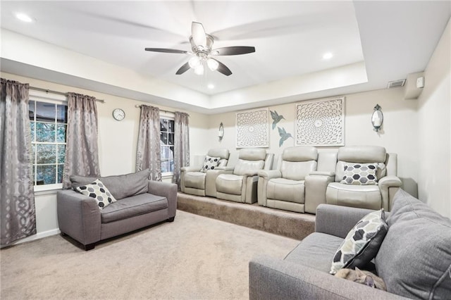 carpeted home theater featuring ceiling fan and a tray ceiling