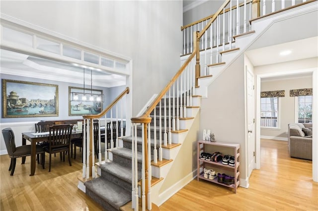 stairs with a chandelier, wood-type flooring, and ornamental molding