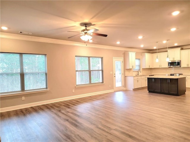 kitchen featuring pendant lighting, white cabinets, a kitchen island, light wood-type flooring, and crown molding