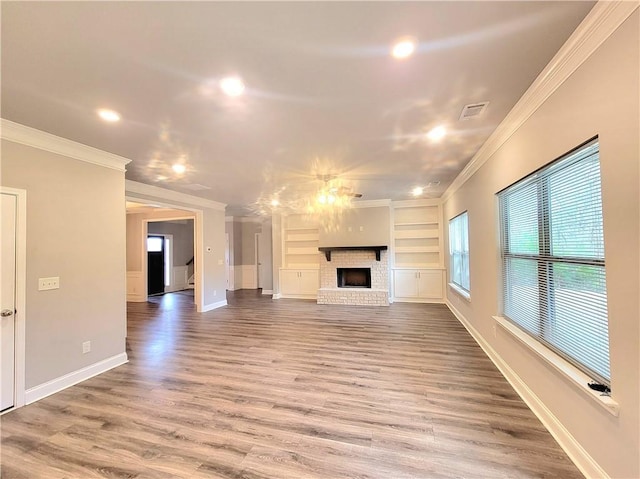 unfurnished living room featuring a fireplace, built in features, hardwood / wood-style flooring, and ornamental molding