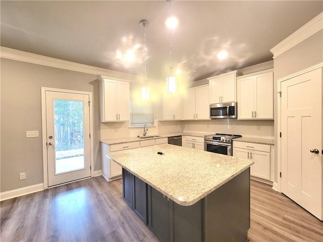 kitchen featuring white cabinets, appliances with stainless steel finishes, a kitchen island, decorative light fixtures, and sink