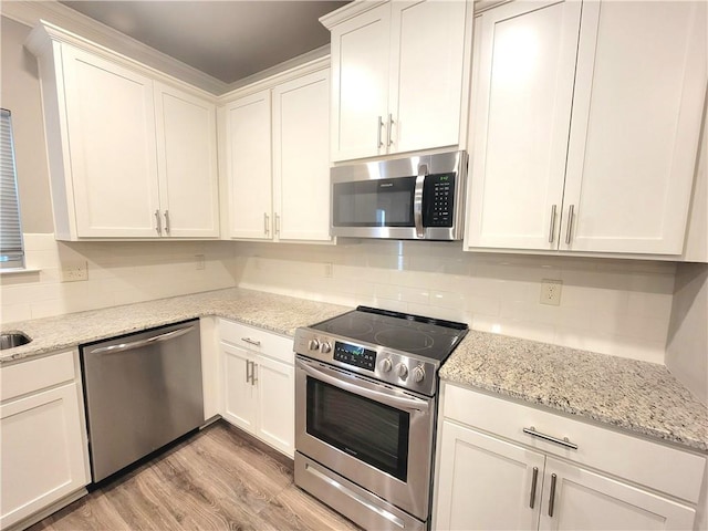 kitchen with light hardwood / wood-style floors, white cabinets, appliances with stainless steel finishes, and light stone countertops