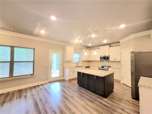 kitchen featuring light hardwood / wood-style floors, sink, a kitchen island, pendant lighting, and stainless steel appliances