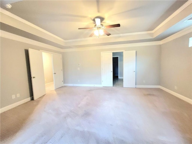 carpeted spare room with ceiling fan, a tray ceiling, and ornamental molding