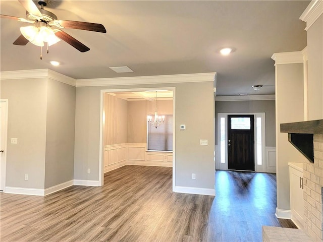 entrance foyer featuring wood-type flooring, ceiling fan with notable chandelier, a fireplace, and ornamental molding