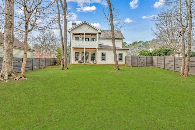 rear view of property with a ceiling fan, a balcony, a fenced backyard, a chimney, and a yard