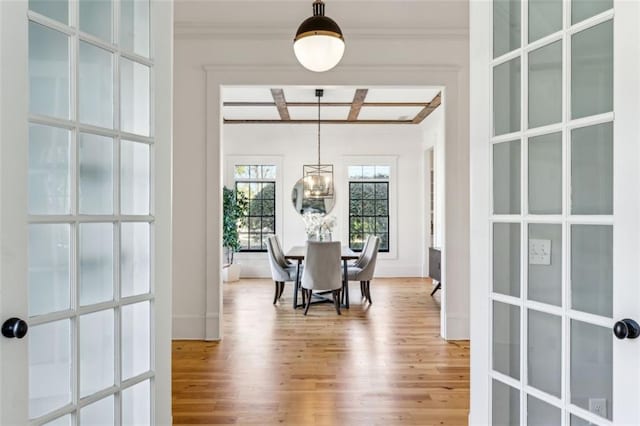 dining area with light wood finished floors, french doors, ornamental molding, and a chandelier