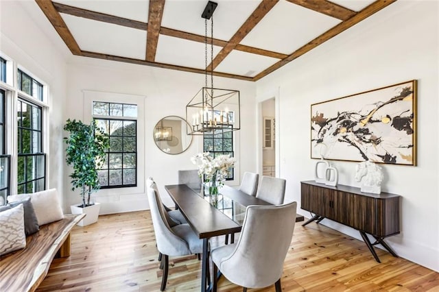 dining area featuring light wood-style floors, a chandelier, coffered ceiling, and beamed ceiling