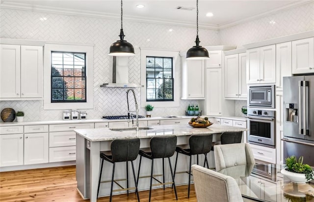 kitchen featuring stainless steel appliances, visible vents, ornamental molding, white cabinets, and wall chimney exhaust hood