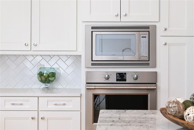 kitchen featuring stainless steel appliances, backsplash, and white cabinetry