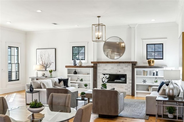 living room featuring crown molding, visible vents, a fireplace, and light wood finished floors