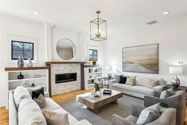 living area featuring a tile fireplace, wood finished floors, visible vents, and crown molding