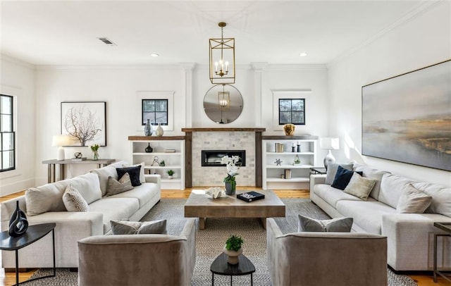 living area with a fireplace, recessed lighting, visible vents, ornamental molding, and wood finished floors