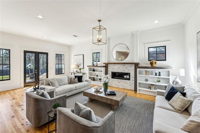 living area featuring recessed lighting, ornamental molding, wood finished floors, and a glass covered fireplace