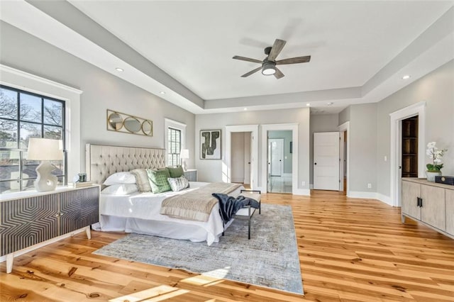 bedroom featuring light wood-style floors, recessed lighting, a raised ceiling, and baseboards