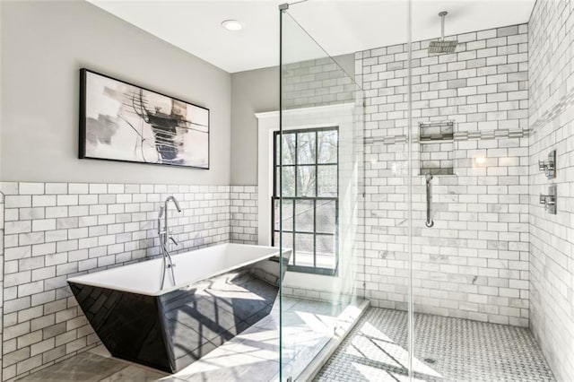 full bathroom featuring a soaking tub, a shower stall, tile patterned flooring, and tile walls