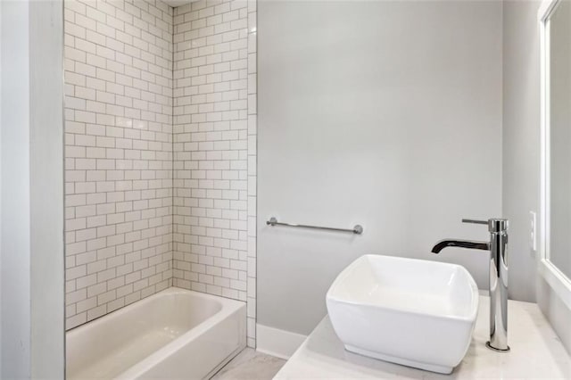 bathroom featuring shower / tub combination, baseboards, and a sink