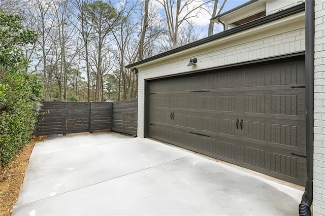 garage with driveway, a gate, and fence