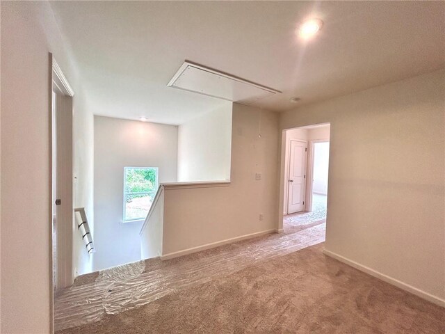 carpeted spare room with baseboards and attic access