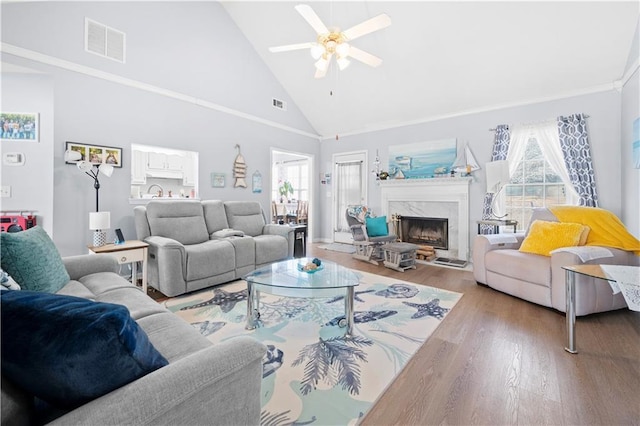 living room with high vaulted ceiling, light wood finished floors, a premium fireplace, and visible vents