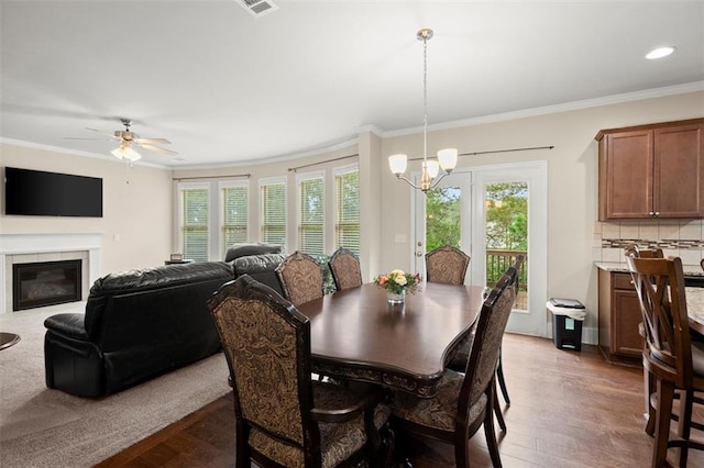 1709 Grove Ct SE, Conyers, GA 30013 - dining room with wood finished floors, ornamental molding, a chandelier, a glass covered fireplace, and a ceiling fan
