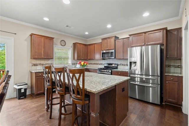 1709 Grove Ct SE, Conyers, GA 30013 - kitchen featuring appliances with stainless steel finishes, dark wood-type flooring, a kitchen island, tasteful backsplash, and light stone counters