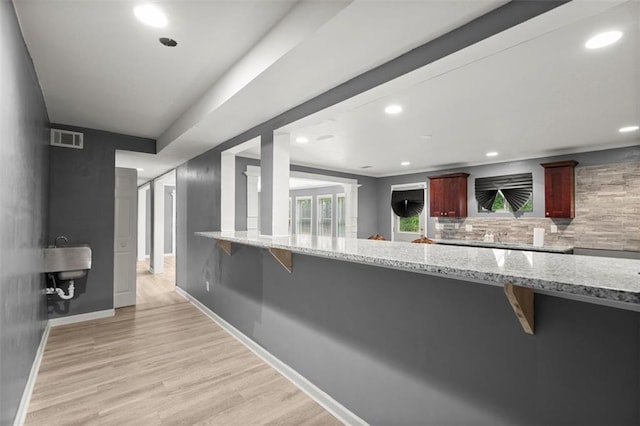 1709 Grove Ct SE, Conyers, GA 30013 - kitchen featuring a kitchen breakfast bar, light wood finished floors, recessed lighting, backsplash, and light stone counters