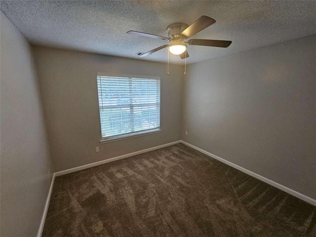 spare room featuring a textured ceiling, dark colored carpet, and ceiling fan