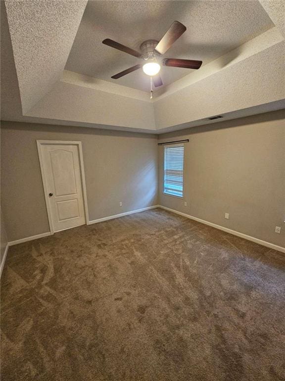 carpeted empty room with a textured ceiling, ceiling fan, and a tray ceiling