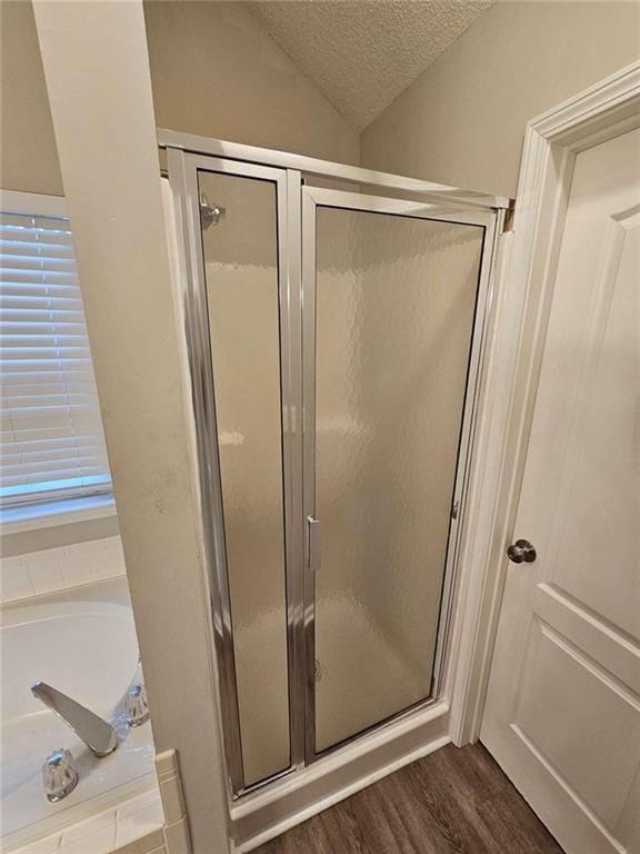 bathroom featuring hardwood / wood-style floors, shower with separate bathtub, lofted ceiling, and a textured ceiling