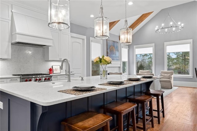 kitchen with white cabinetry, range, custom exhaust hood, and a large island with sink